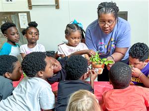 kids with ms. ruby and a plant